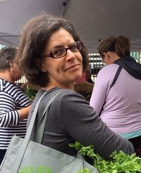 Melinda Nettles, artist and illustrator, proprietor of LEAN2creativeworks, at the farmers' market, with carrot tops, in Eugene, Oregon.